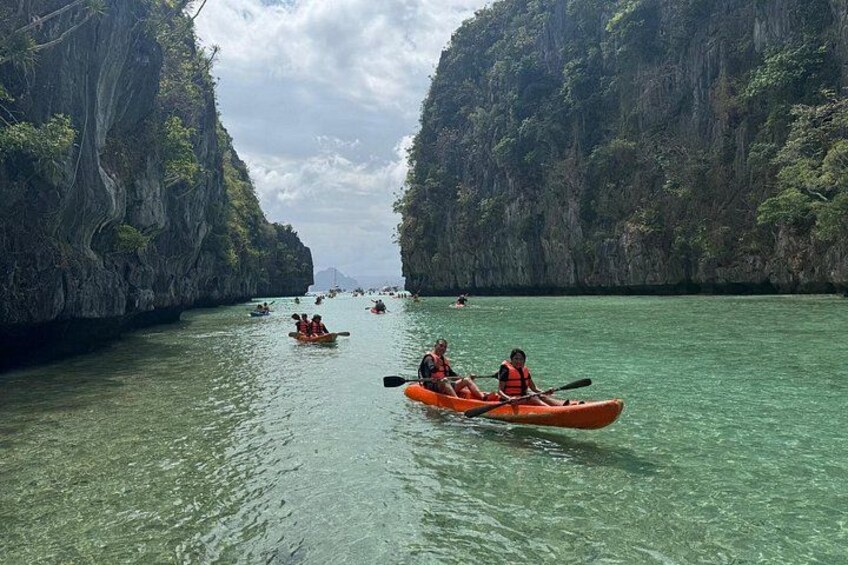 Kayakers on a clear river surrounded by rocky cliffs. 5