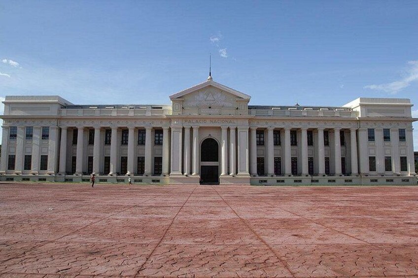 A large, white building with a central entrance and columns, surrounded by a paved area. 4