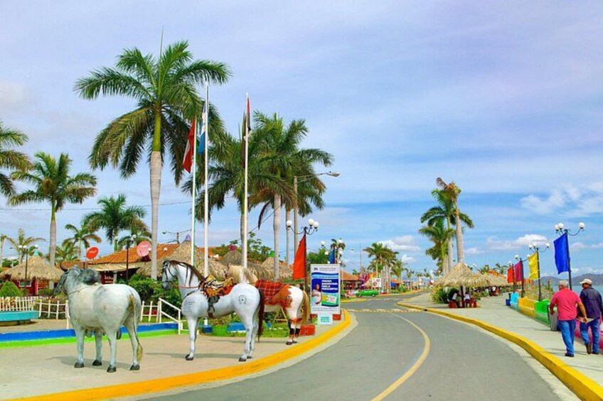 A road with palm trees, flags, and a horse statue. 3