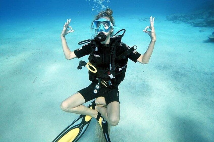 A person scuba diving underwater, wearing a black wetsuit and fins, with a diving mask and breathing apparatus. 3