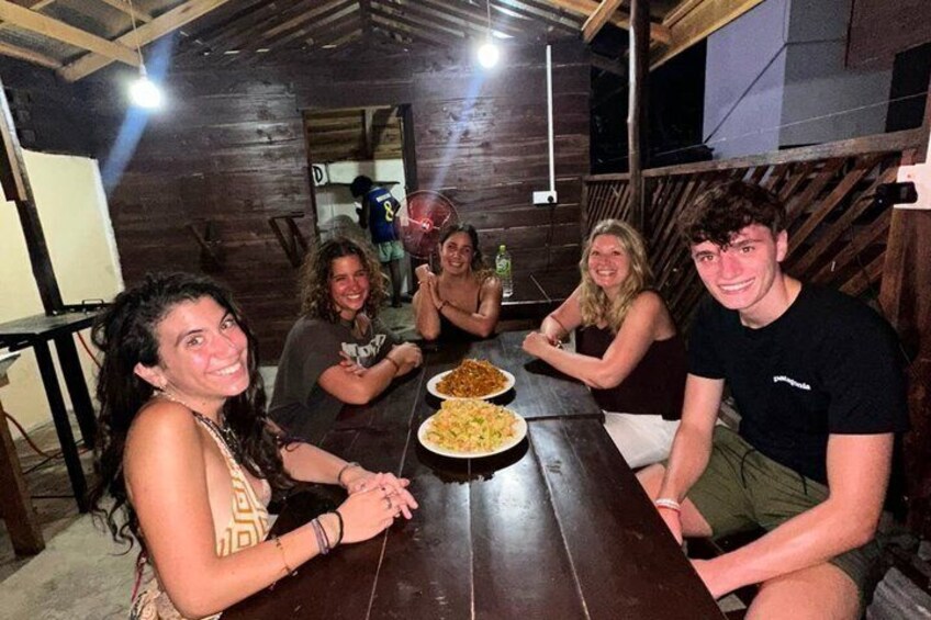 Een groep mensen zit rond een houten tafel met eten. 5