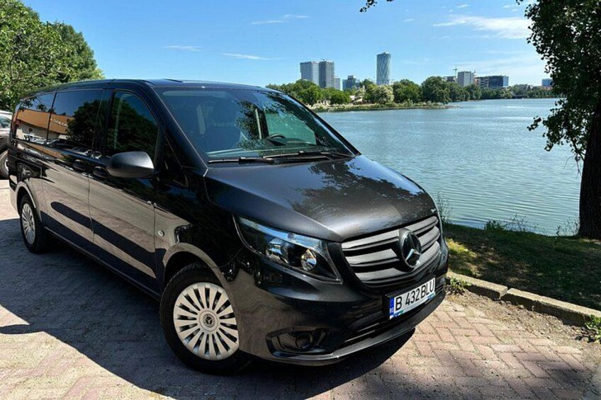 A black Mercedes-Benz van parked by a lakeside with a city skyline in the background. 5