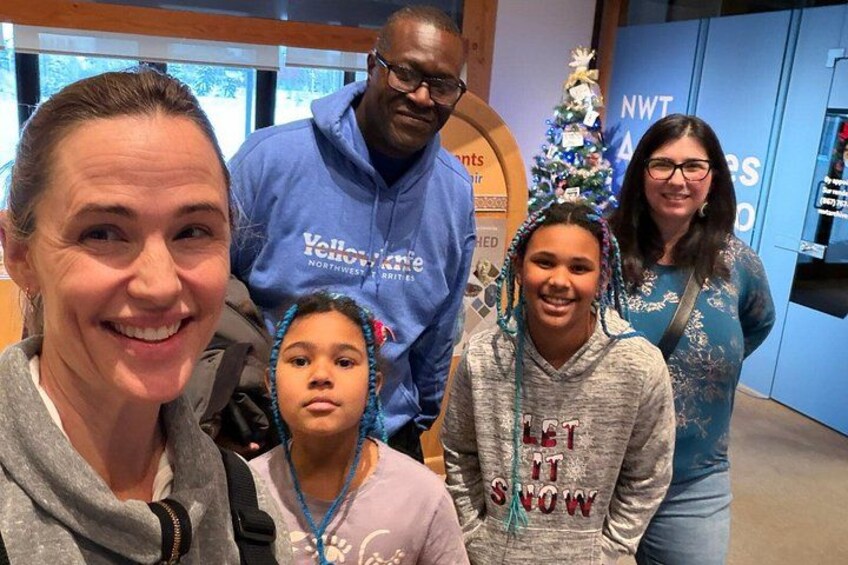 A group of people in a room with a Christmas tree and a sign that reads 'NWT.' 3