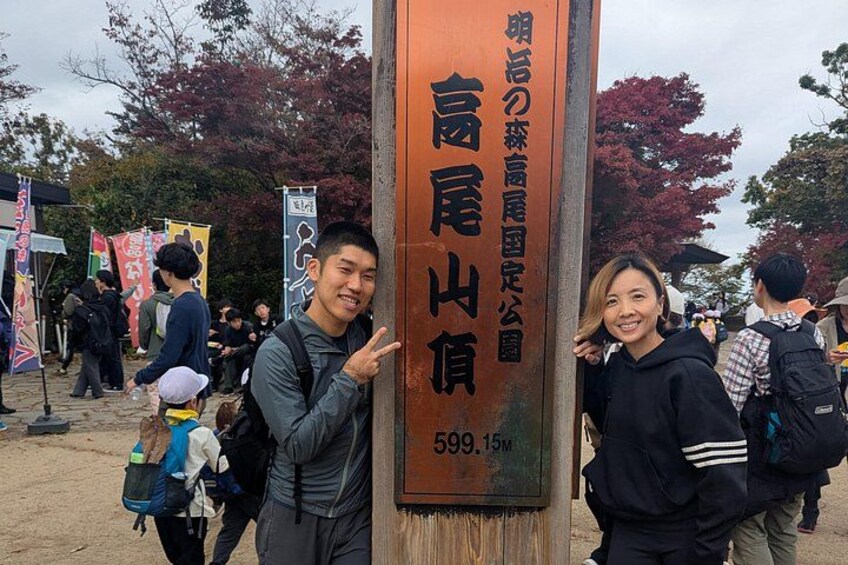 Two people posing in front of a sign with Japanese text and a height marker. 3