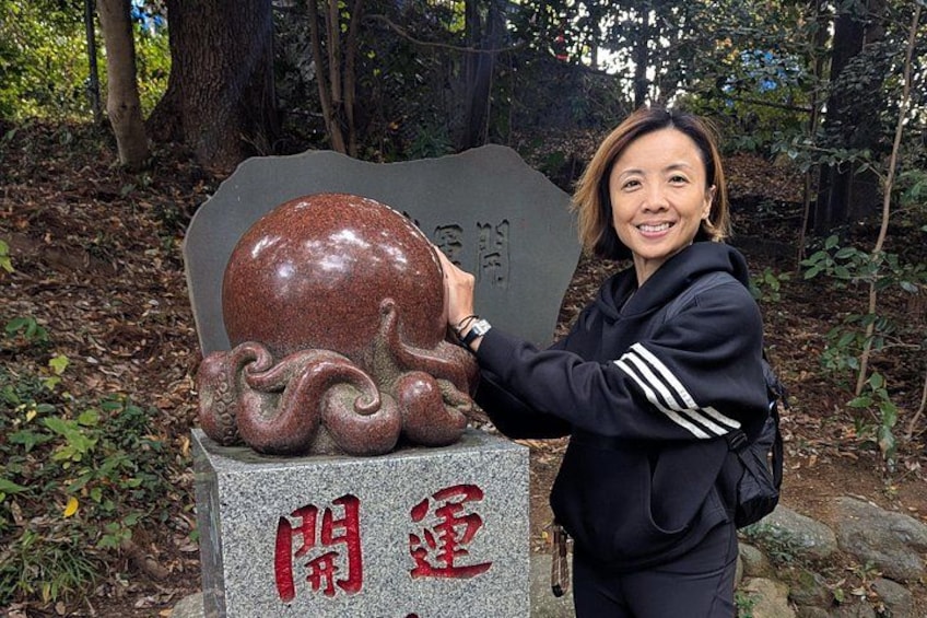 A person standing next to a stone monument with a large, spherical object and Chinese characters. 2