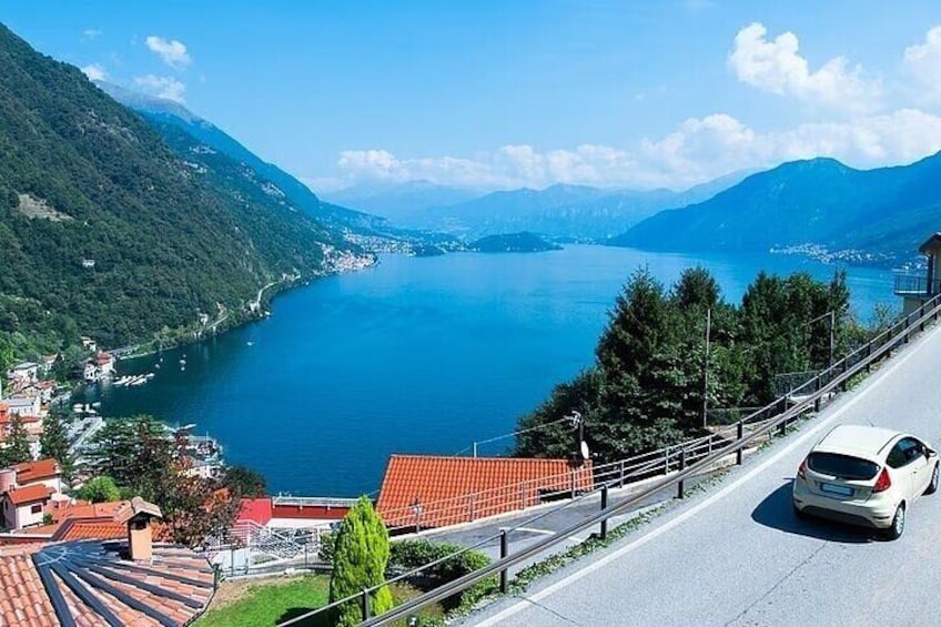 A road with a car, a lake, and mountains in the background. 4