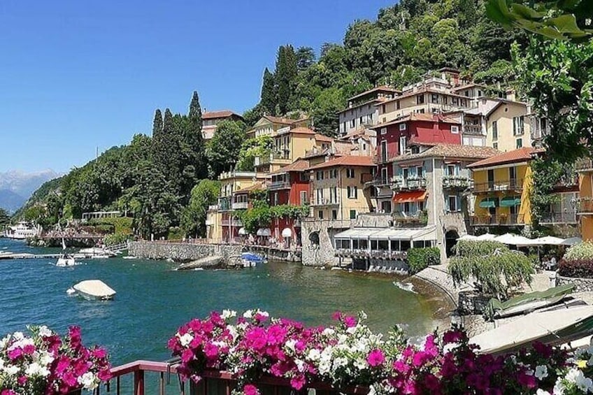 A lakeside town with colorful buildings, boats, and blooming flowers. 2