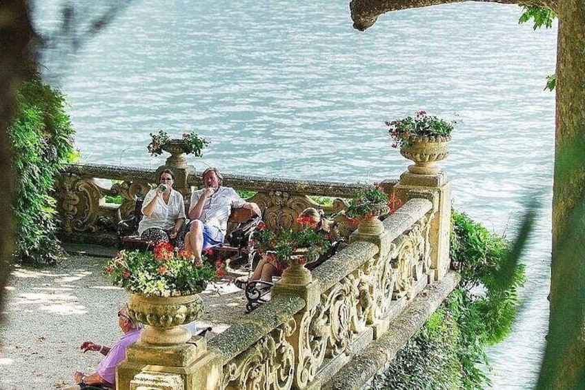 A stone balustrade with ornate carvings, a body of water, and potted plants. 5