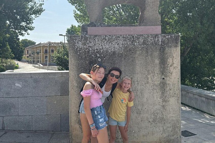 A group of people posing in front of a stone structure with a building in the background. 5