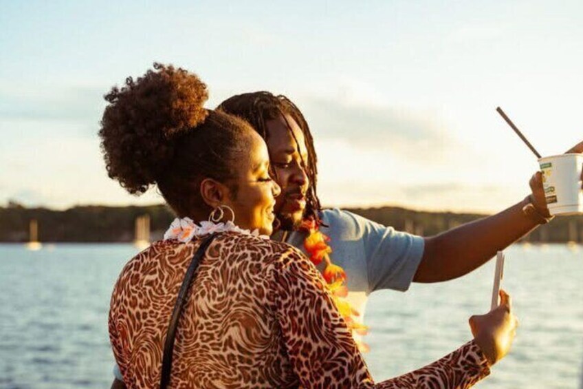 Two people taking a selfie by a body of water with a bridge in the background. 3