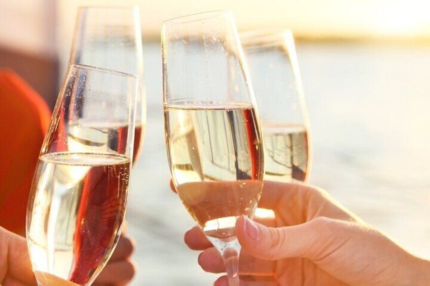 Two hands holding champagne flutes filled with a light-colored beverage, likely champagne, against a blurred background. 2