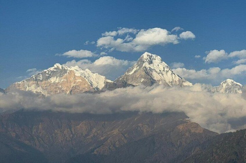A mountain range with snow-capped peaks and clouds below. 5