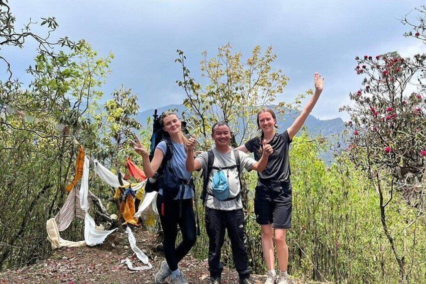 Three people hiking with backpacks, surrounded by trees and a mountainous landscape. 4