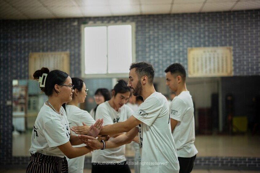 A group of people in a room with patterned walls and a window. 1