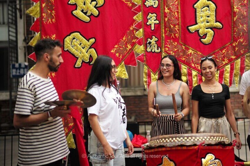A group of people performing a traditional dance with red and gold banners in the background. 5