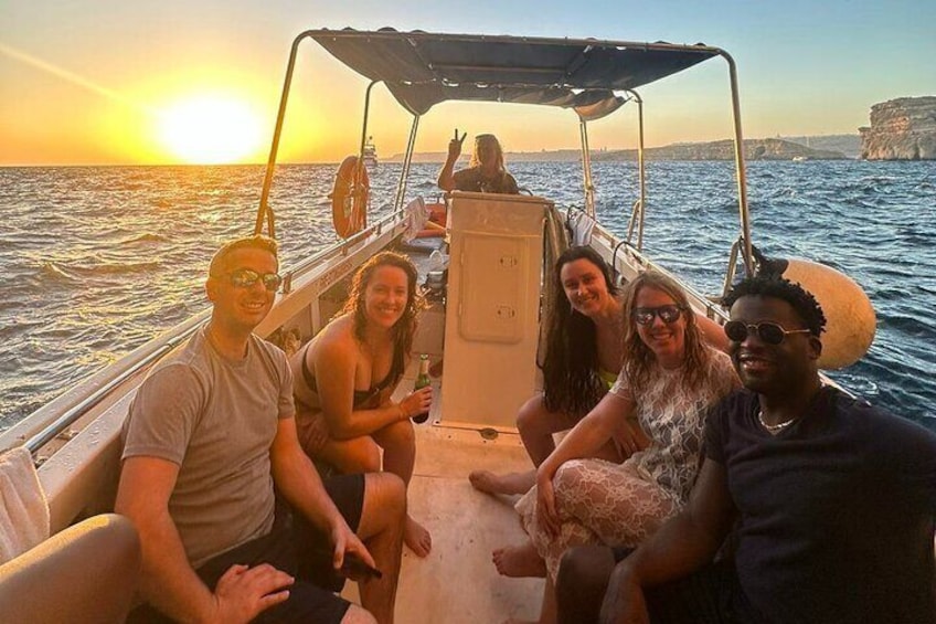 A group of people on a boat with the sun setting in the background. 1