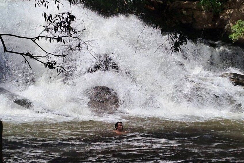 A person swimming in a river with a waterfall in the background. 2