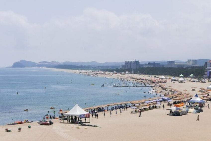 A beach with tents, people, and boats. 2