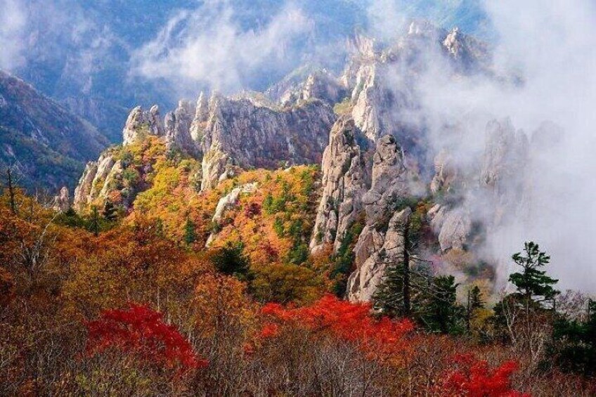 A mountainous landscape with autumn foliage and rocky cliffs. 4