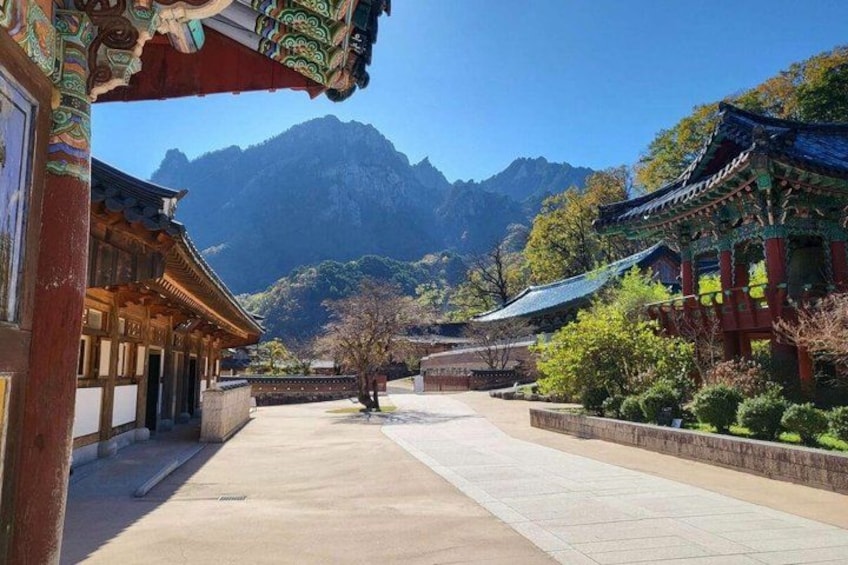 A traditional Korean temple complex with wooden architecture, a stone pathway, and a mountain backdrop. 5