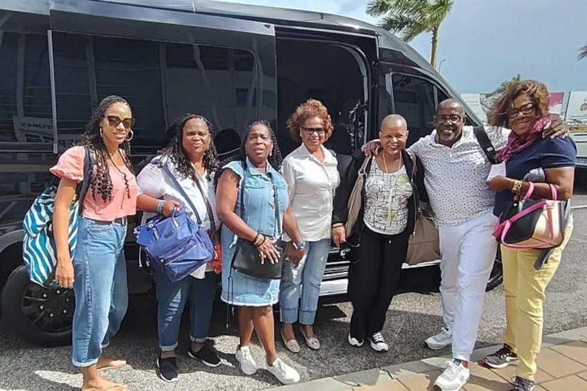 A group of people standing in front of a black van. 1