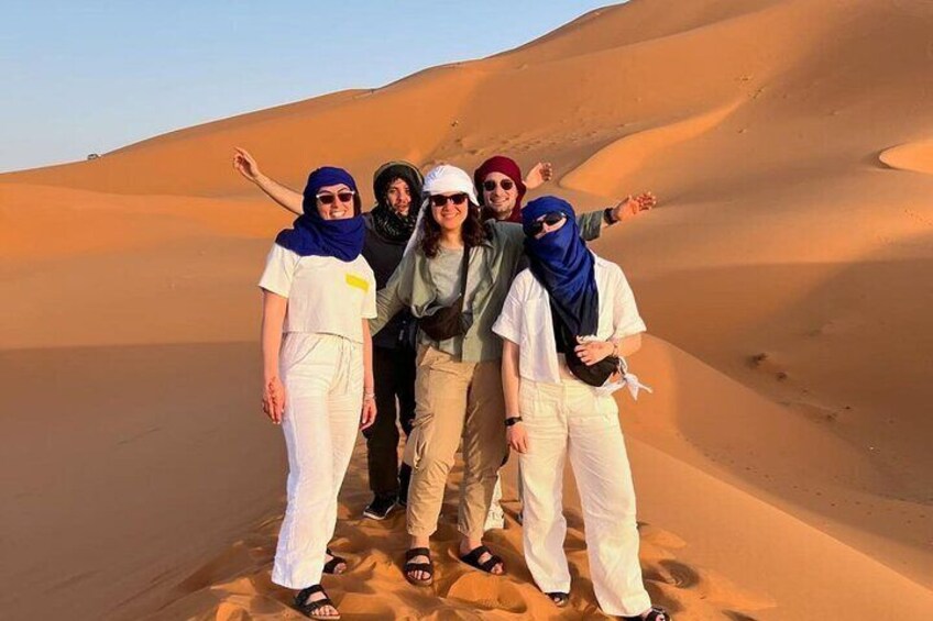 A group of people standing on a sand dune with a desert landscape in the background. 4