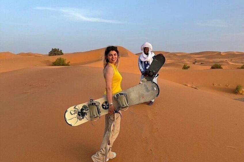 A person holding a snowboard in a desert landscape. 5