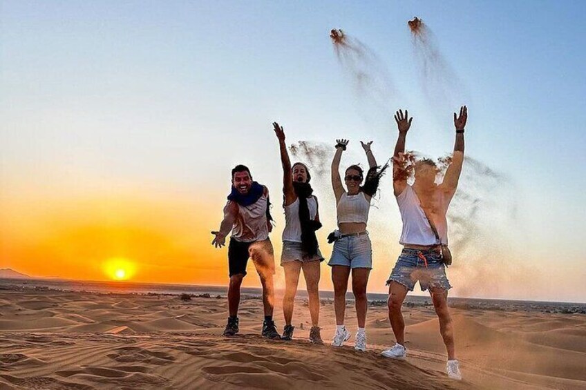 Four people jumping in the sand at sunset. 2
