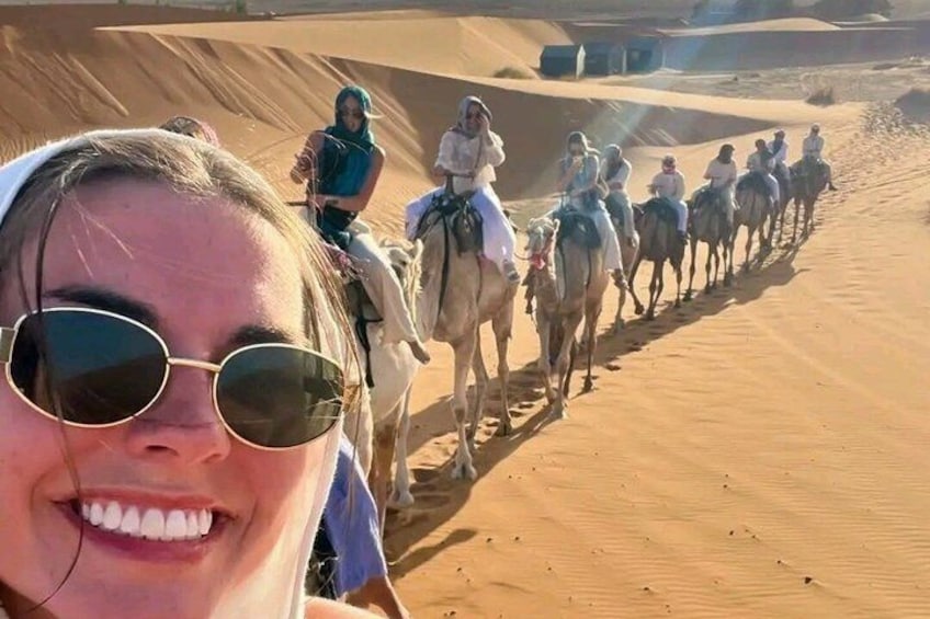 A group of people riding camels through a desert landscape. 1