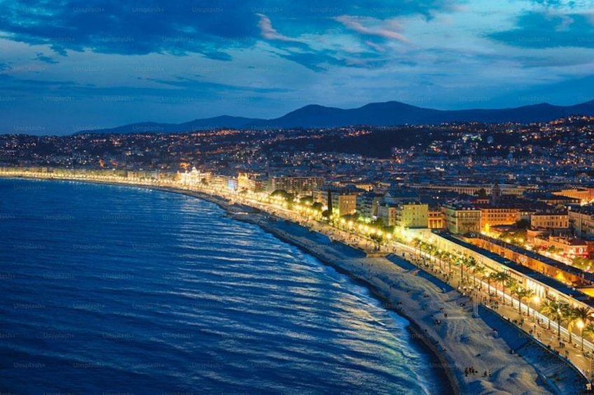 A coastal cityscape at night with a beach, illuminated buildings, and a mountain in the background. 5