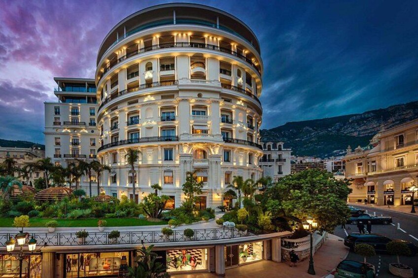 A multi-story hotel with balconies, surrounded by greenery and a mountainous backdrop. 4