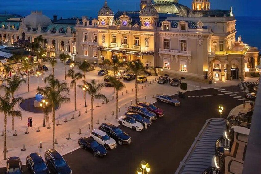 A grand hotel with a large dome and ornate architecture, a parking lot with several cars, and palm trees lining the street. 3
