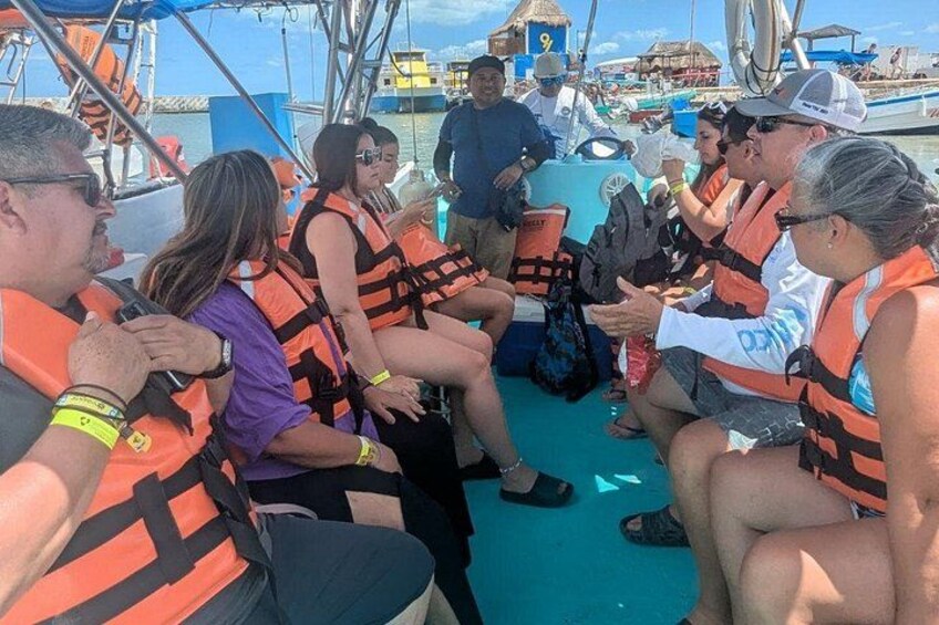 Des personnes à bord d’un bateau portent des gilets de sauvetage, certaines tiennent des appareils photo, et une bâche bleue est déployée sur le pont. 5