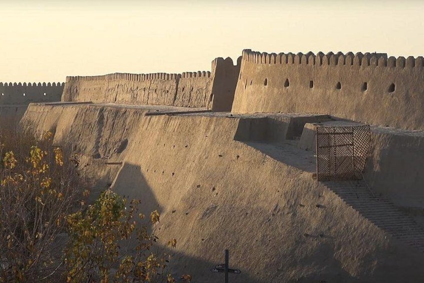 Een hoge, oude stenen muur met een poort en een trap die erheen leidt. 3