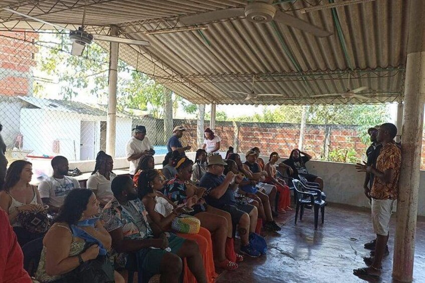Un espacio al aire libre cubierto con gente sentada y de pie, escuchando a un orador. 1