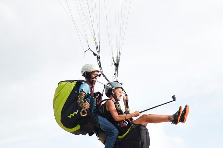 Two people paragliding with a large green and black parachute. 2
