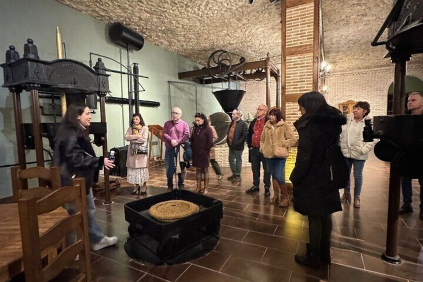 A group of people touring a historical exhibit with industrial machinery and artifacts. 1