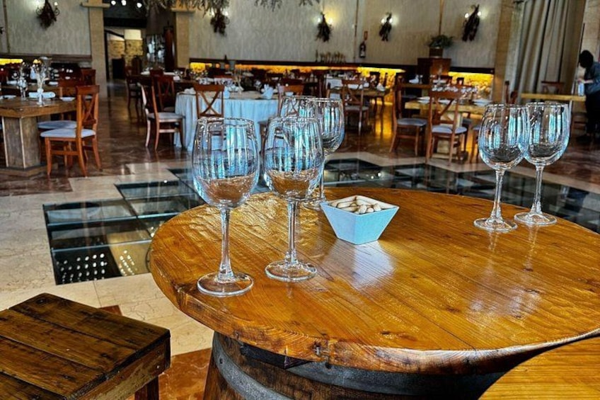 A restaurant interior with round tables, wine glasses, and a blue bowl. 2