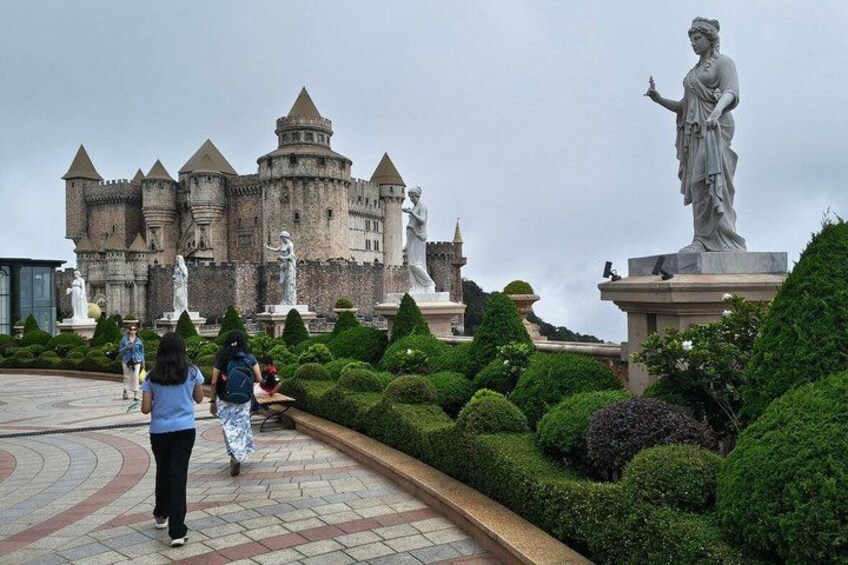 A castle with statues and manicured hedges. 5