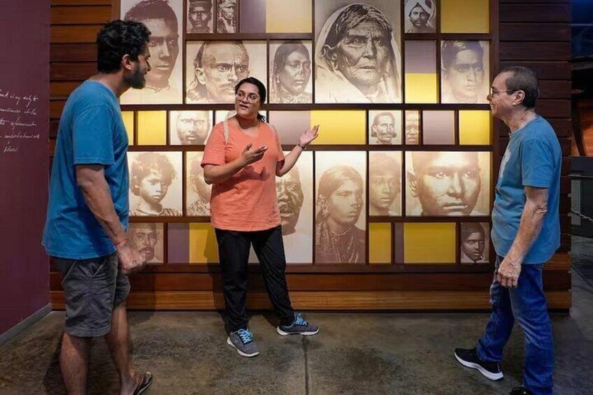 Three people in a museum with a wall of portraits. 4