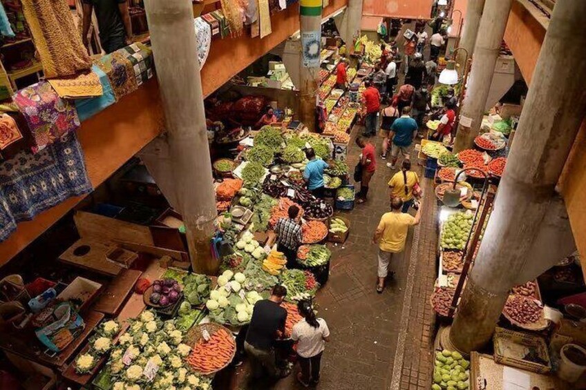An indoor market with various stalls selling fruits and vegetables. 5