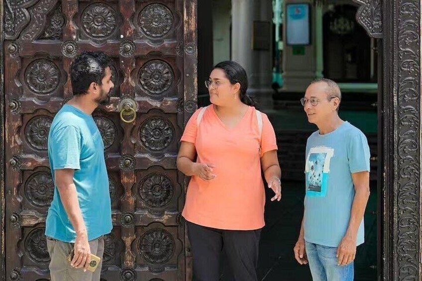 Three people standing in front of a large, ornate door. 3