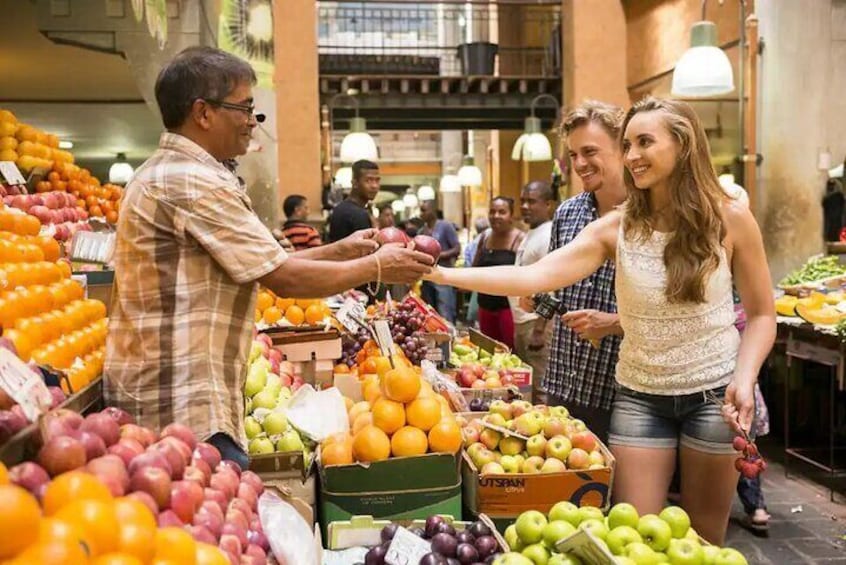 A fruit market with various fruits like apples, oranges, and grapes on display. 1