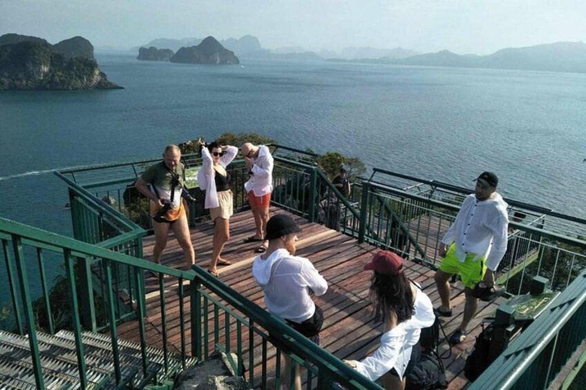 Un grupo de personas en una cubierta de madera con vistas a un cuerpo de agua y islas distantes. 3