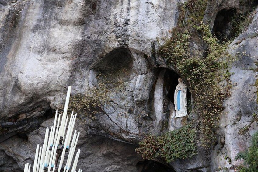 Una formación rocosa con una abertura similar a una cueva, una estatua y una cerca blanca. 4