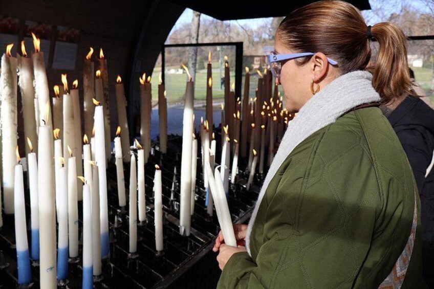 Una persona sostiene una vela encendida frente a una hilera de velas. 5