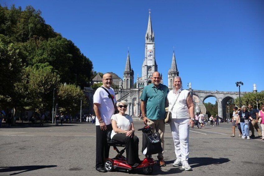 Un grupo de personas en una plaza pública, con una iglesia histórica y un puente al fondo. 1