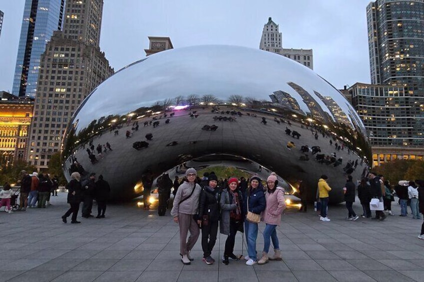 A large metallic sculpture with people posing in front of it. 1
