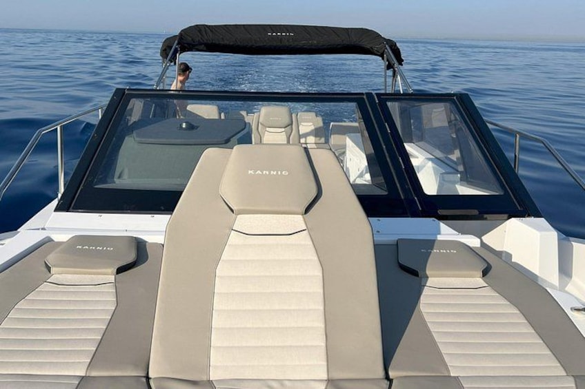 A boat with a canopy, beige seats, and the brand name 'KARNIC' on the backrest. 1