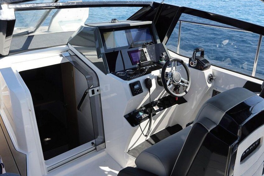 A boat's interior with a steering wheel, control panel, and seating. 4